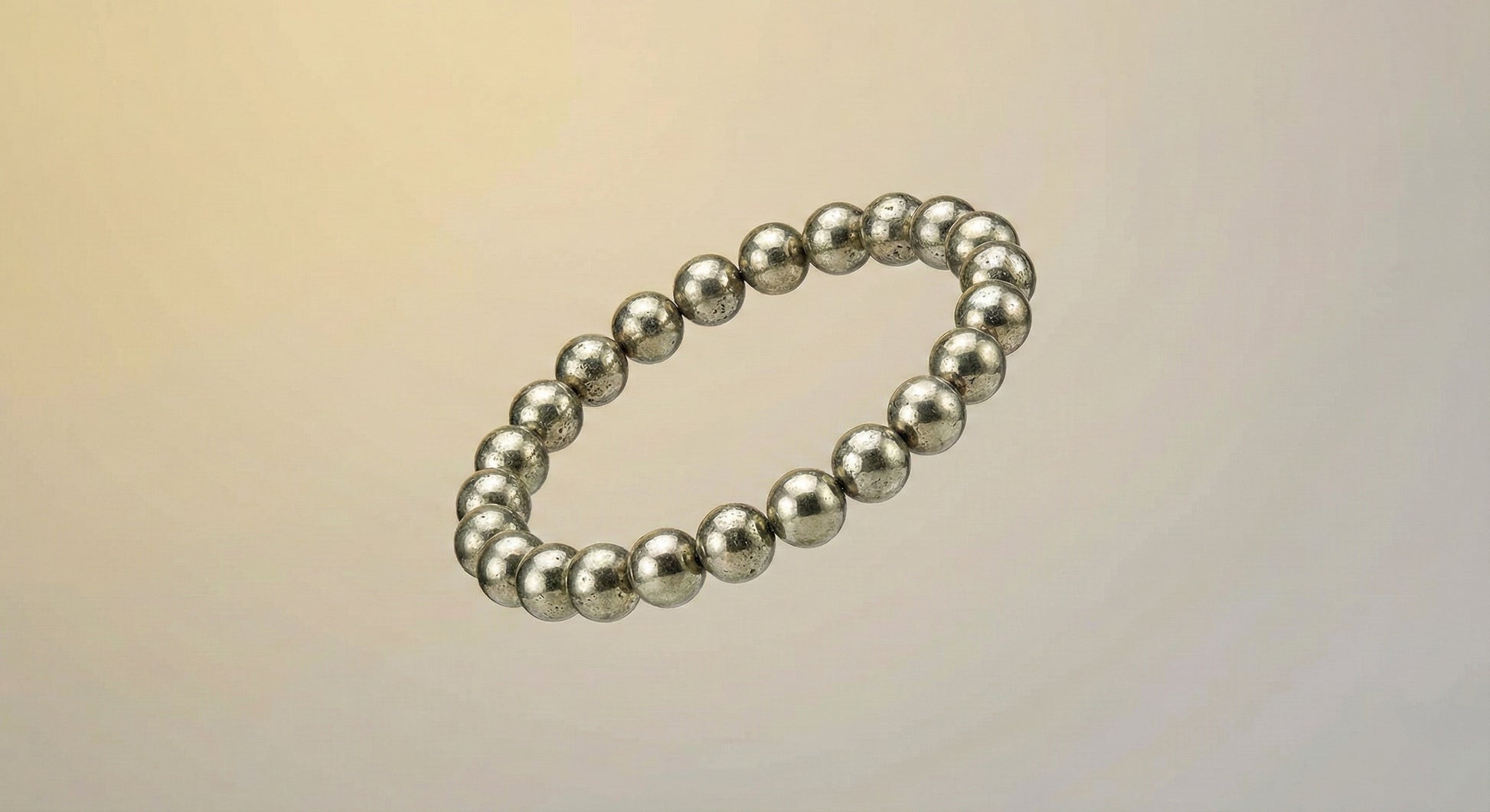 Silver metallic bead bracelet on neutral gradient background