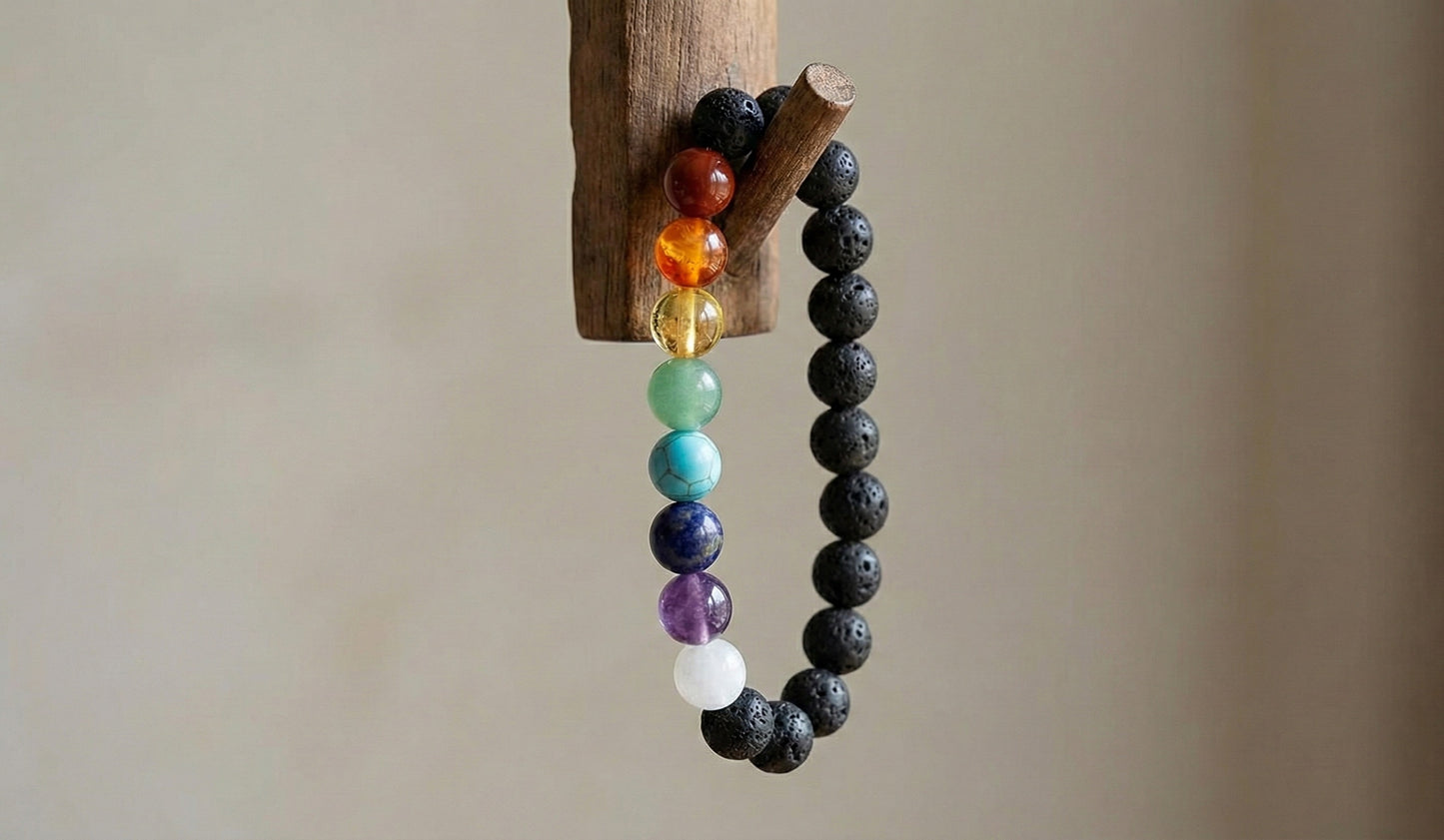 chakra bracelet with multicolored stones and black lava beads hanging on wooden hook