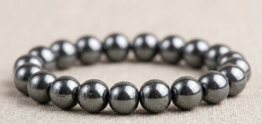 Close-up of a shiny metallic hematite bead bracelet on beige fabric background