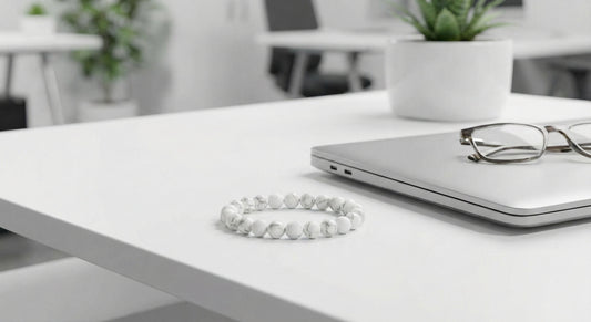 White marble bead bracelet on white office desk beside closed laptop and eyeglasses