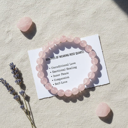 Pink rose quartz bracelet on white card listing benefits with lavender sprigs and quartz stones