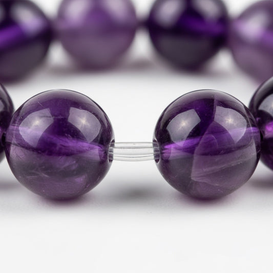 Close-up of polished purple amethyst gemstone beads strung on clear elastic cord