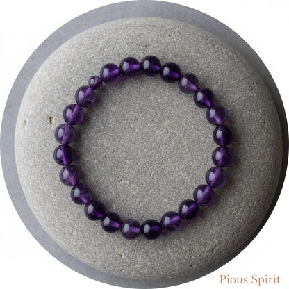 Purple amethyst bead bracelet displayed on a smooth gray stone with round shape
